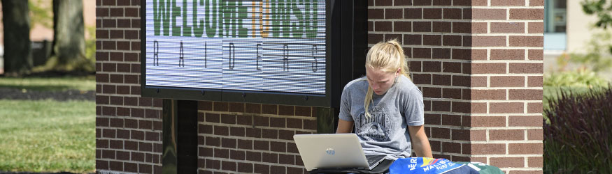 photo of a student sitting outside with a laptop