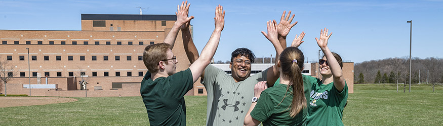 photo of students high-fiving on a field