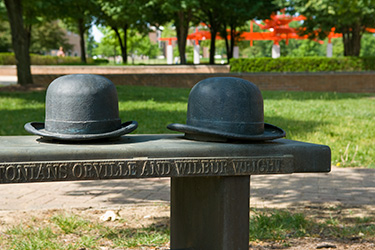 photo of bench with wright bros hats on campus