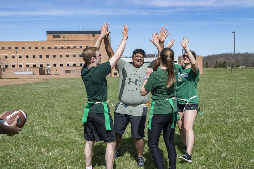 photo of students high-fiving on the football field