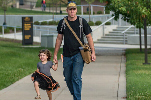 Father walking his young daughter on campus