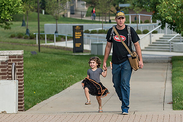 Student walking his daughter on campus