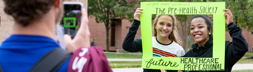 Two female students posing in selfie frame at Fall Fest event