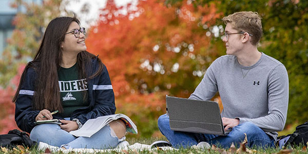 two students sitting outside on campus