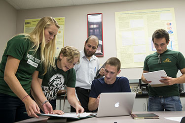 photo of students and a professor around a table