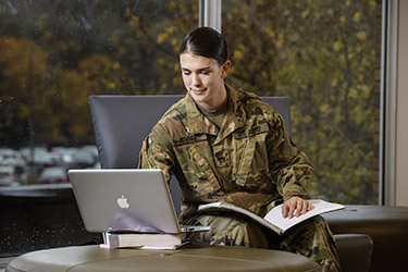 photo of a student studying with a book and laptop