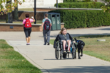 photo of a student with a service dog on campus