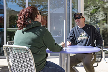 photo of students sitting at a table outside on campus