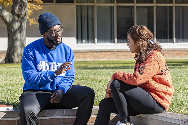 photo of two students sitting outside on campus