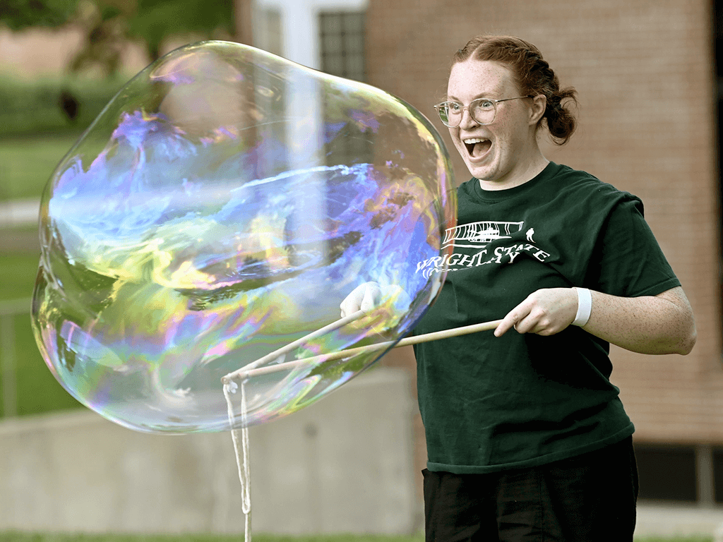 Student blowing huge bubbles with a rope wand
