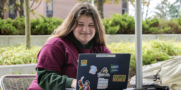 photo of a student sitting outside using a laptop