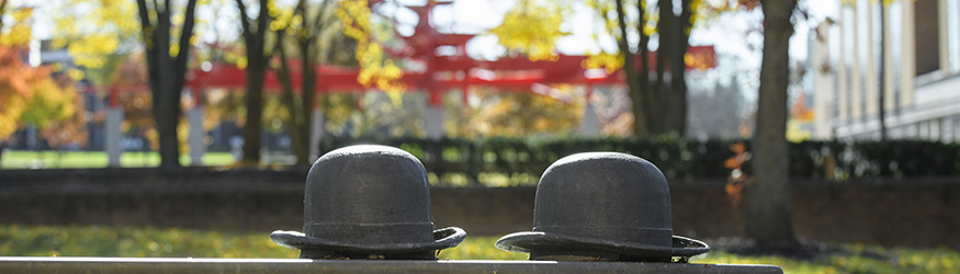 photo of the bowler hats on a bench on campus
