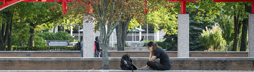 photo of a student sitting outside using a laptop