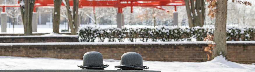 photo of bowler hats on bench on campus