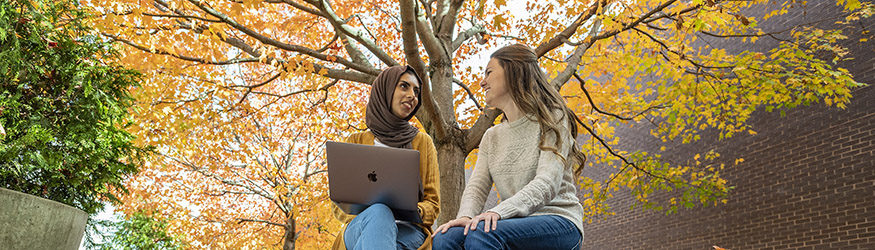photo of two students sitting outside on campus 