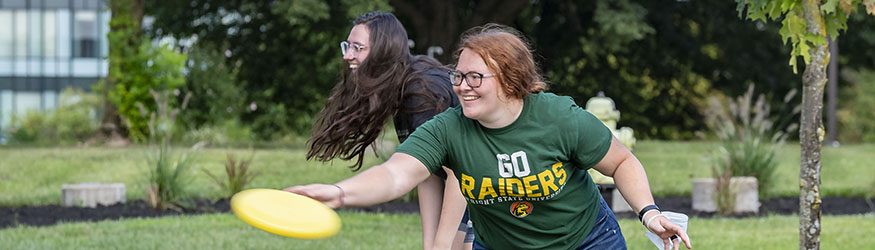 photo of students playing frisbee on campus