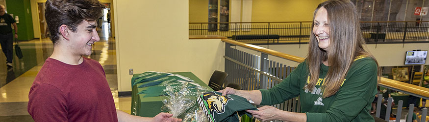 photo of a staff member giving a student a tshirt at an event in the student union