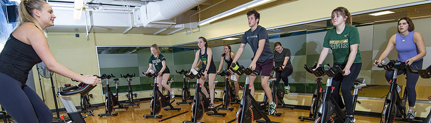 photo of an instructor and students in a cycling class