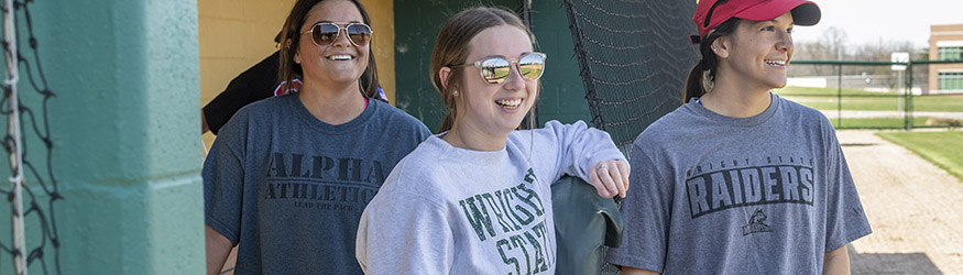 photo of students in the dugout of the softball field