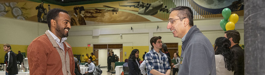 photo of a student and faculty member talking at an open house