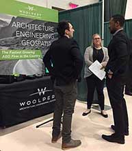 Photo from Career Fair 2018 Spring Semester, featuring a student talking to recruiters from Woolpert.