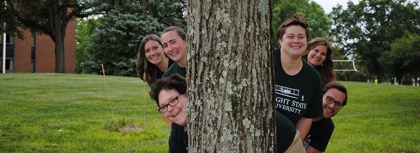 Residence Life Staff peeking out from behind a tree