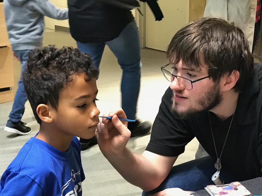 Student painting child's face