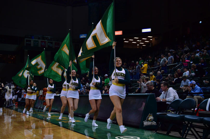 Cheerleaders running with flags to spell Raiders