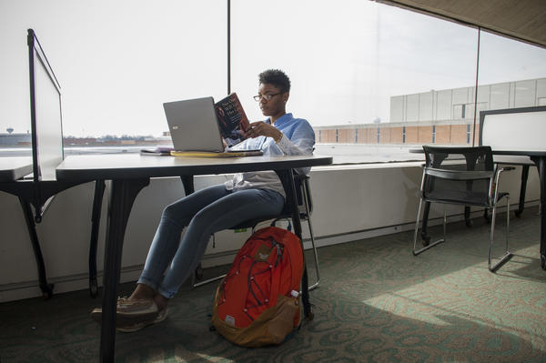 Virtual Spotlight Event Student sits at laptop, with book