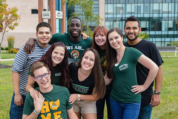 students smiling in front of the alumni tower