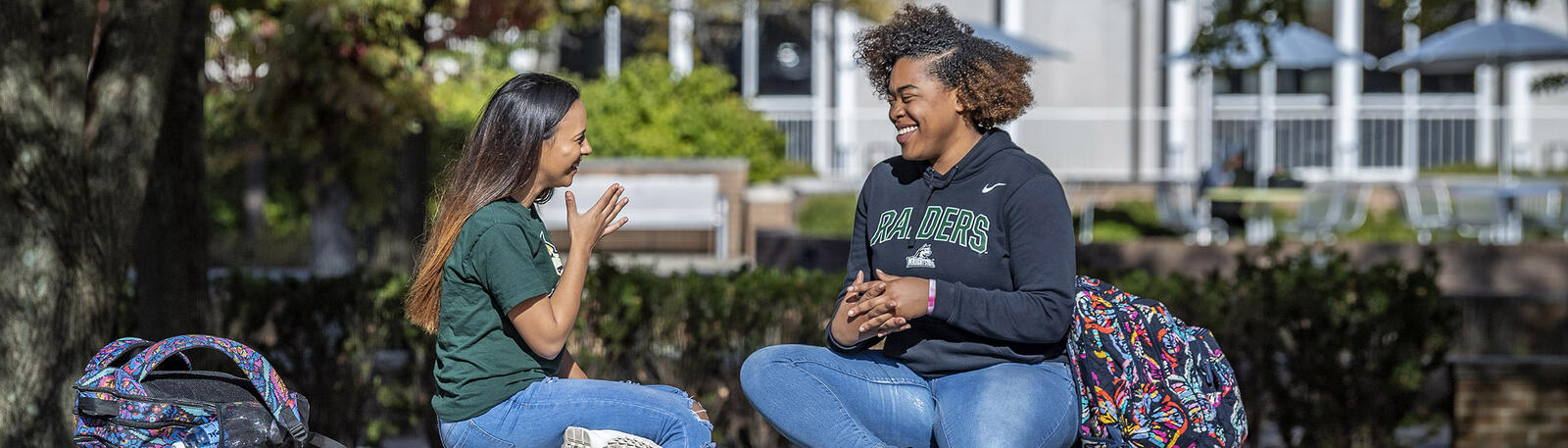 photo of two students sitting outside on campus