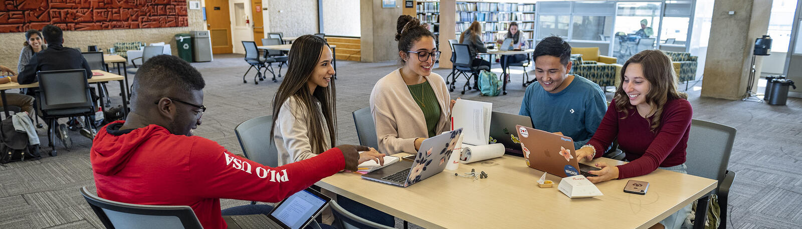 group of students using laptops at a table in the library