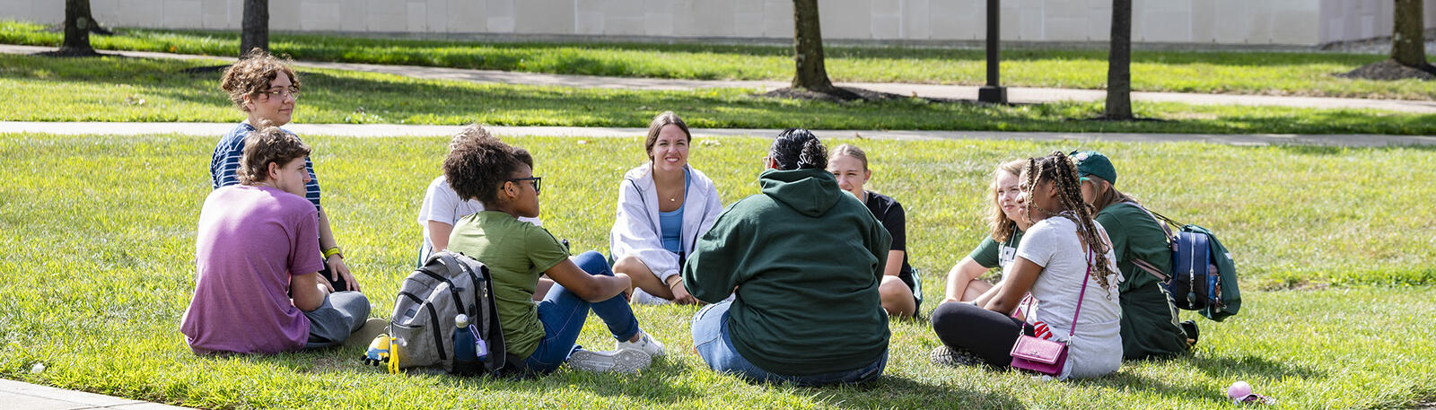 students sitting in a circle on the lawn on campus