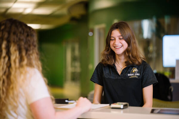 student employee helping someone check in at campus recreation