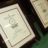Two framed Golden Spoke Awards on a table. 