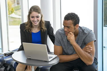 photo of two students looking at a laptop