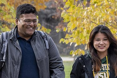 two students walking across campus in the fall