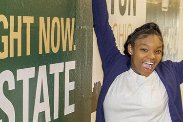 student cheering next to Raider mural