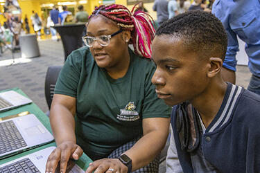 two students sitting together looking at a computer