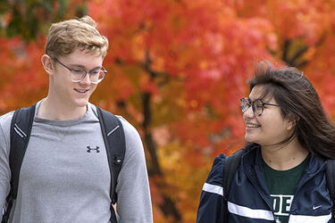 two students walking across campus in the fall