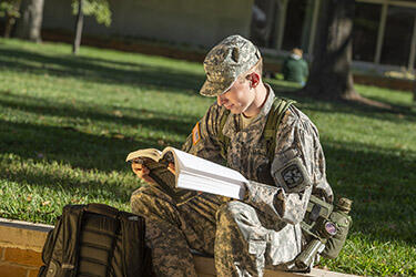 photo of a student reading a book outside on campus