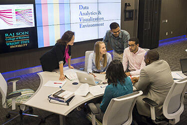 photo of students and a professor in the data analytics and visualization environment 