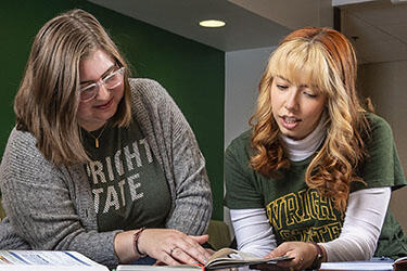 photo of two students looking at a textbook