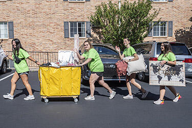 photo of students carrying items on move in day