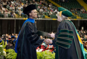 Sue Edwards shakes hands with a graduate