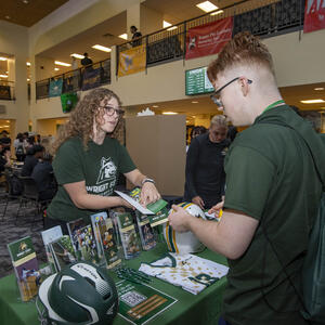 a student receiving a brochure and talking to someone at an event