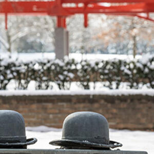 photo of bowler hats on bench on campus