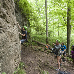 photo of student climbing the rock into the woods 