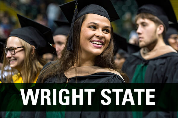 Woman smiling wearing her cap and gown graduating at her masters graduation